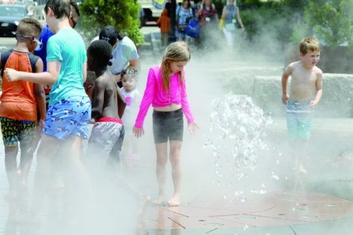 Children play in a city water feature during a heatwave in Boston